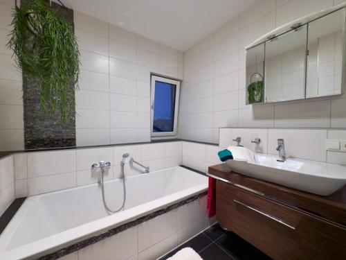 a white bathroom with a tub and a sink at Thermenblick in Bad Aibling