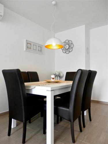 a dining room table with black chairs and a light fixture at Luna Apartment in Poreč