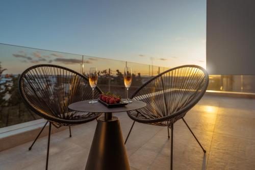 two chairs and a table with two glasses of wine at The White Loft - Cretan Luxury in Ierápetra