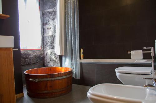 a bathroom with a wooden tub next to a toilet and a sink at Aldeia Dos Caldeirões in São Mateus