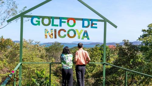 a man and woman standing in front of a sign that reads colombo niwa at Nicoya Silvestre in Lepanto