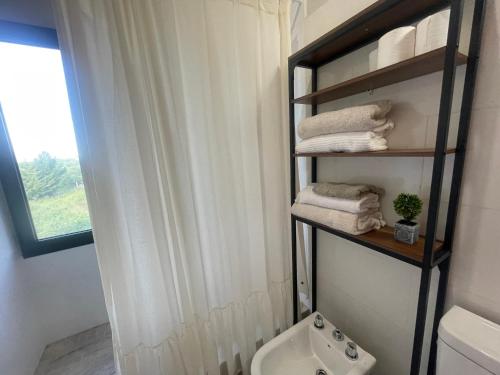 a bathroom with a toilet and a shelf with towels at Verdena in Villa Amancay