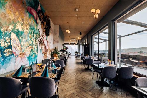 a restaurant with tables and chairs and a large mural at sgrafit hotel - Self Check-In in Retz