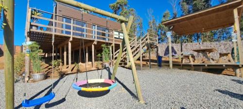 a playground with two swings in front of a building at Algarrobo Tinaja Caliente Privada Lista para Disfrutar in Tunquen