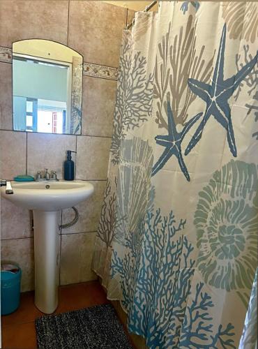 a bathroom with a sink and a shower curtain with starfish at Grandvistasuites Tobago in Scarborough