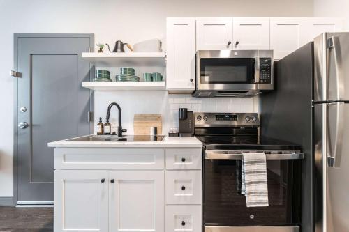 Una cocina con gabinetes blancos y un refrigerador de acero inoxidable. en Bold and Bright Stay with Cher & Etta James Flair, en Macon