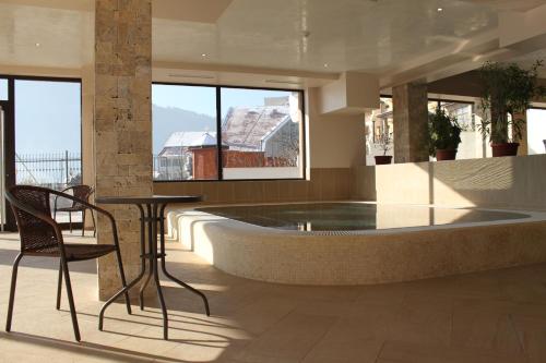 a hot tub in a room with a table and chairs at Park Hotel and SPA Vella Hills in Velingrad