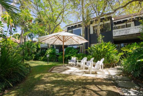 a patio with chairs and an umbrella in front of a house at Emerald Inn on Takapuna Beach in Auckland