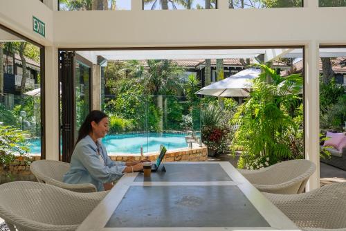 a woman sitting at a table with a laptop at Emerald Inn on Takapuna Beach in Auckland