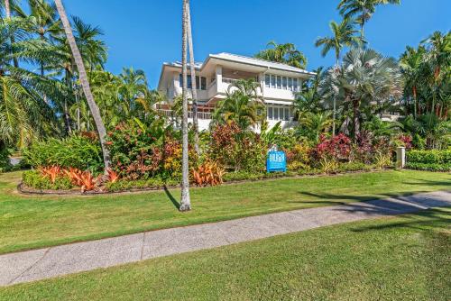 a house with palm trees in front of a yard at Balboa Apartments in Port Douglas