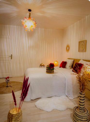a bedroom with a white bed with two vases at Grande maison romantique avec jacuzzi intérieur & parking, à 1h30 de Paris in Montbouy