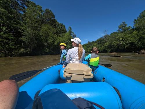 a group of people in a blue raft on a river at Riversong Cabin - Living Waters Farm in Cleveland