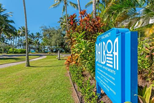 a sign in front of a park with palm trees at Balboa Apartments in Port Douglas