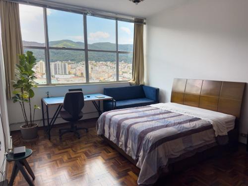 a bedroom with a bed and a desk and windows at Apto no Centro, Conforto e Estilo in Poços de Caldas