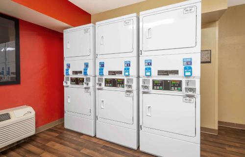 four white refrigerators are lined up against a red wall at Extended Stay America Suites - Princeton - West Windsor in Princeton