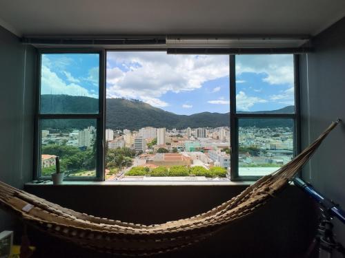 a hammock in a room with a view of a city at Apto no Centro, Conforto e Estilo in Poços de Caldas
