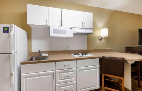 a kitchen with white cabinets and a sink and a refrigerator at Extended Stay America Suites - North Chesterfield - Arboretum in Richmond