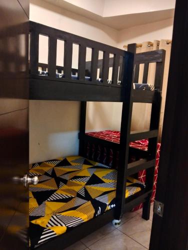 a black bunk bed with a yellow and black patterned blanket at Goshen Land Towers Baguio in Baguio