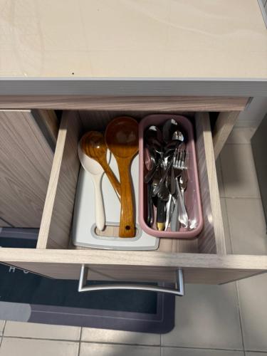 a drawer filled with utensils in a cabinet at Homestay Zailin A'Famosa in Kampong Pulau Sebang