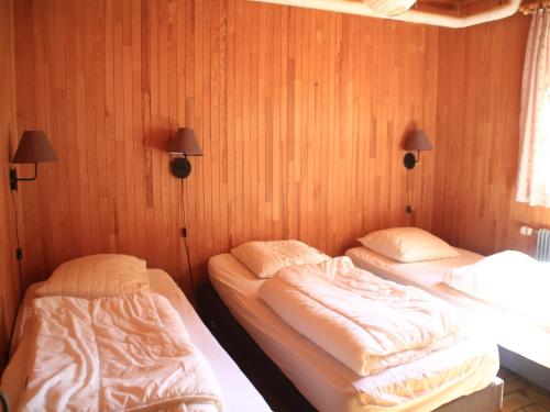 two twin beds in a room with wood paneling at Chalet in Vonnes near Chairlifts & Shuttle in Châtel