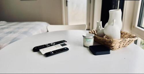 a table with a remote control a cell phone and a remote at Cozy & Lux 1 Bed Studio Retreat in Weston Creek