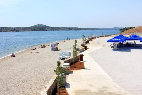 Una playa con sombrillas azules y gente en la playa. en Seaside holiday house Sibenik - 23990, en Šibenik