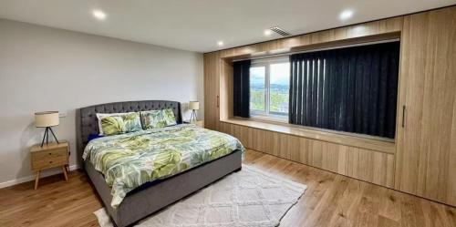 ein Schlafzimmer mit einem Bett und einem großen Fenster in der Unterkunft 4Bedroom Luxury home with Comfort & Stylish in Weston Creek