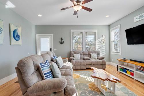 a living room with two couches and a flat screen tv at Turtle Cove Beach Retreat GOLF CART Included in Carolina Beach
