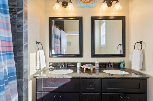 two sinks in a bathroom with two mirrors at Turtle Cove Beach Retreat GOLF CART Included in Carolina Beach
