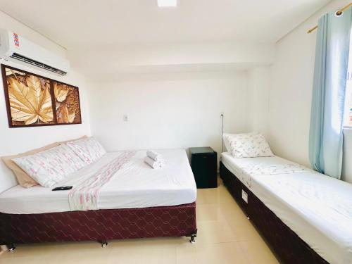 two beds in a room with white walls at Suíte Estrela-do-Mar 2 - Pé na Areia in Maragogi