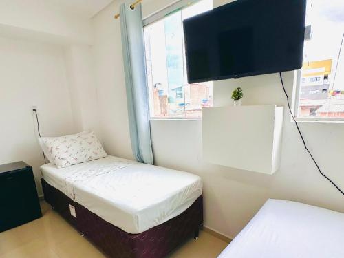 a small room with a bed and a flat screen tv at Suíte Estrela-do-Mar 2 - Pé na Areia in Maragogi
