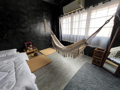 a hammock in a bedroom with a bed and a window at Stay Strays Hostel in Bangkok