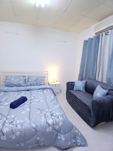 a bedroom with a bed and a couch at Al Ain Mall Transient Studio in Al Ain