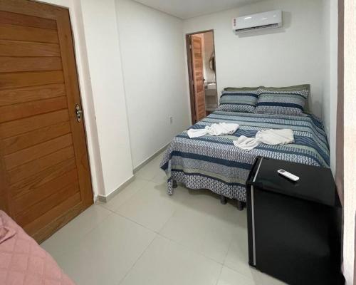 a bedroom with a bed with a black table and a door at Suíte Pôr do Sol 1 - Pé na Areia in Maragogi