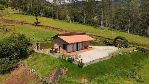 a small house in the middle of a field at Chalé Magia do Serrano in São Bento do Sapucaí