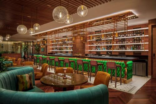 a restaurant with a bar with green chairs and tables at JW Marriott Mumbai Juhu in Mumbai