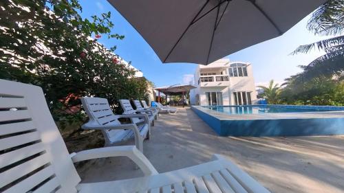 a group of white chairs sitting next to a swimming pool at Beach House in Tela with a Pool in Tela