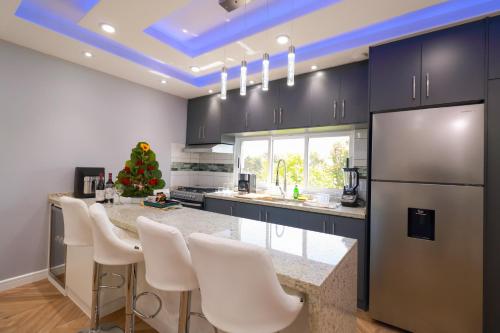 a kitchen with a counter with white chairs and a refrigerator at Espectacular y Moderno Apartamento Paradise a 15 min en vehiculo del Zocalo de Oaxaca in Oaxaca City