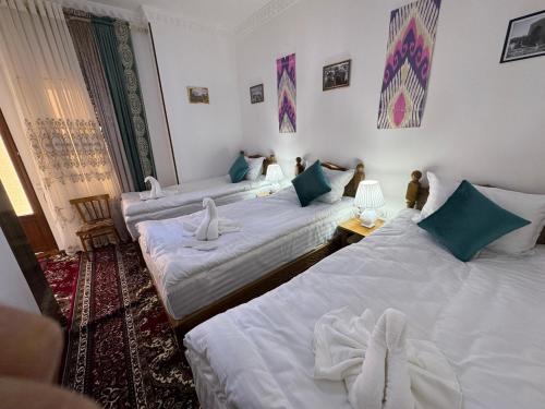 a room with three beds in a room at Bekhzod in Bukhara