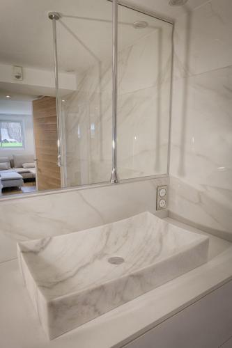 une salle de bain blanche avec un lavabo et un miroir dans l'établissement APPARTEMENTS LOFT OCEAN - Tarnos, à Tarnos