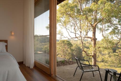 a bedroom with a large window with a view of a tree at Myocum Ridge Farm in Myocum