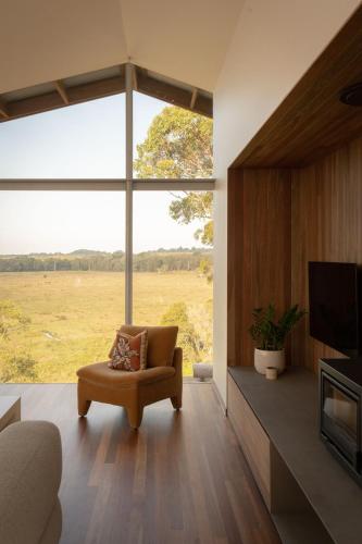 a living room with a couch and a large window at Myocum Ridge Farm in Myocum