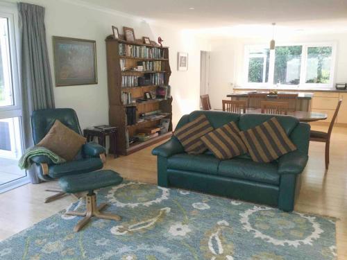 a living room with a green couch and a chair at The Grumpy Trout Lodge #Outdoors on our #doorstep! in Turangi