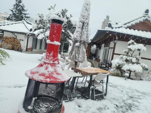 a red and black bird feeder in the snow at Hongcheon Hanok Stay Scenery in Hongcheon