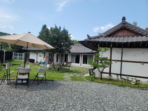 a patio with chairs and an umbrella next to a house at Hongcheon Hanok Stay Scenery in Hongcheon