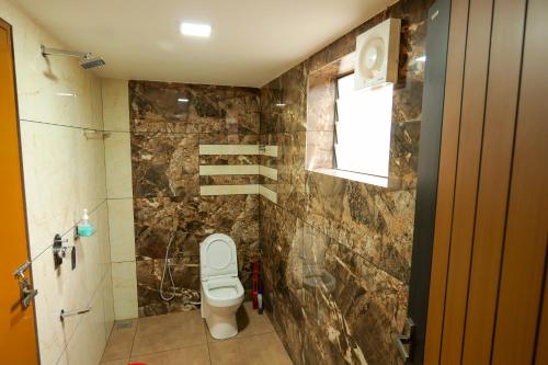 a bathroom with a toilet and a window at MAS Residency in Ernakulam