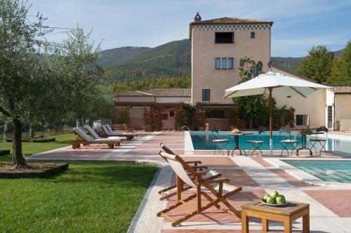 a pool with chairs and an umbrella next to a house at La Tenuta Dei Ciclamini in Avigliano
