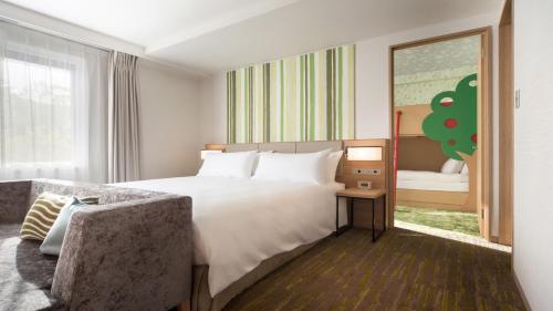 a hotel room with a bed and a chair at Holiday Inn Resort Shinano-Omachi Kuroyon by IHG in Omachi