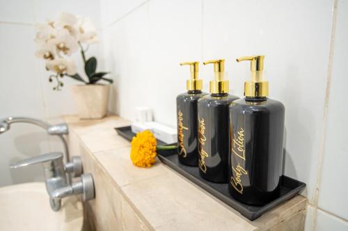 Tres botellas negras en un mostrador en un baño en Suar Villa Ubud, en Ubud