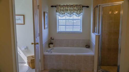 a bathroom with a bath tub and a window at Heron's Nest in Port Saint Lucie